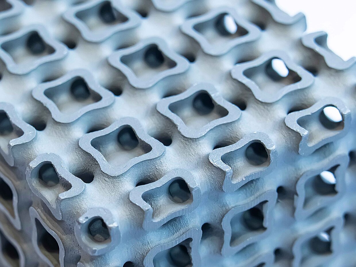 Makroaufnahme eines hellblauen perforierten Würfels, gedruckt auf einem Metall-3D-Drucker