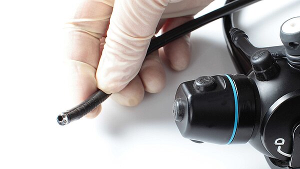 Eine Hand in OP-Handschuh hält ein Endoskop