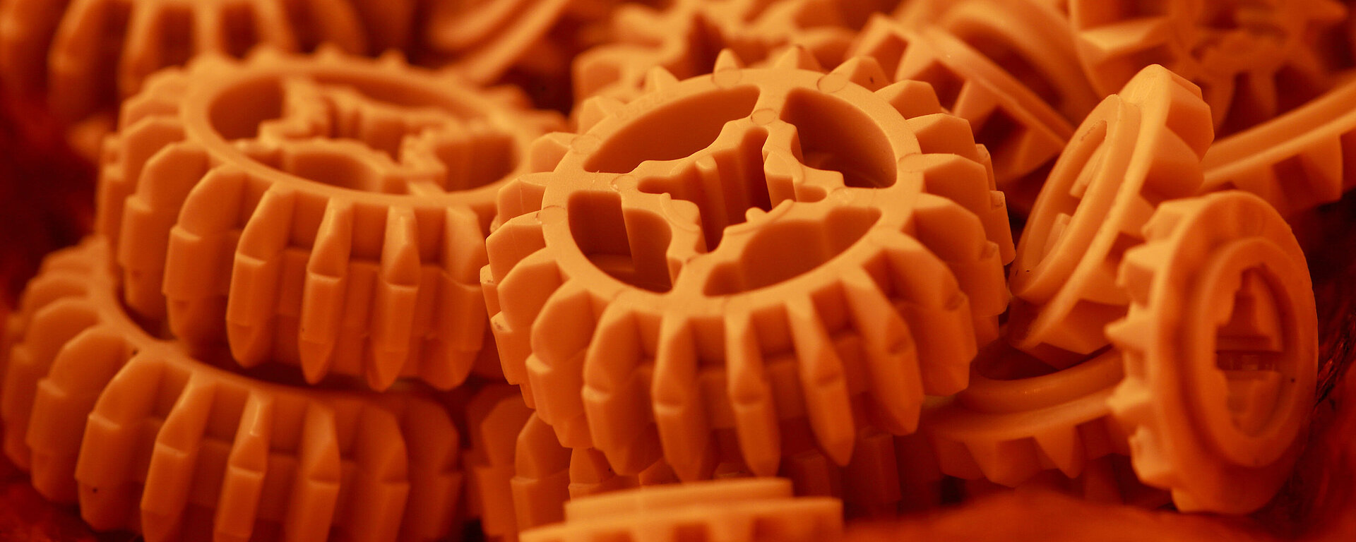 Blick auf eine lose Ansammlung orangefarbener Zahnräder aus Kunststoff