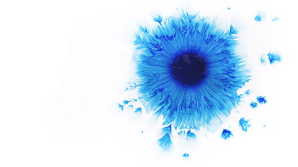 Ein zerfliessender, blauer Farbklecks auf Aquarellpapier 
