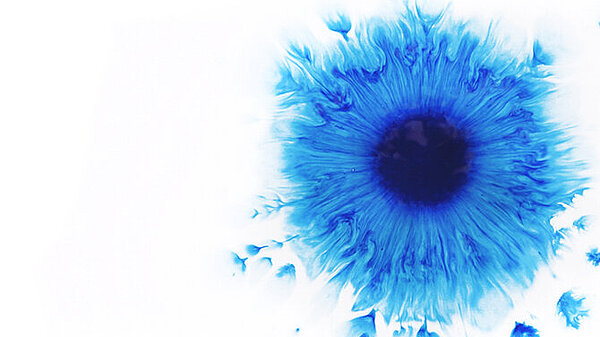 Ein zerfliessender, blauer Farbklecks auf Aquarellpapier 