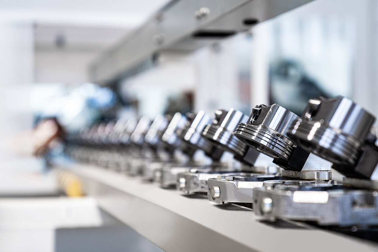 A view of pistons for vehicle engines lined up in a row on an assembly line