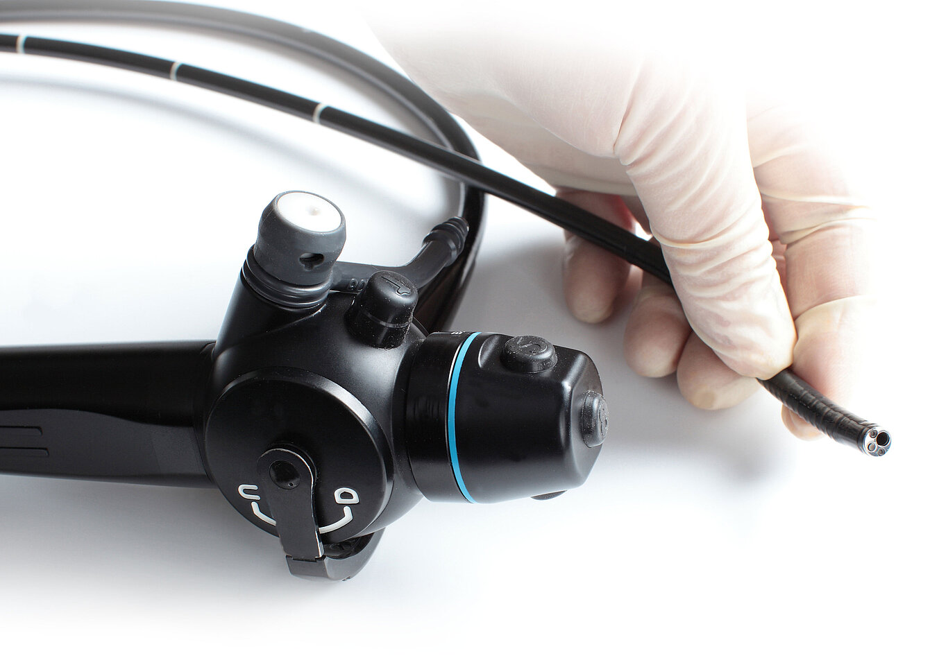 Eine Hand in Latexhandschuh hält ein Endoskop