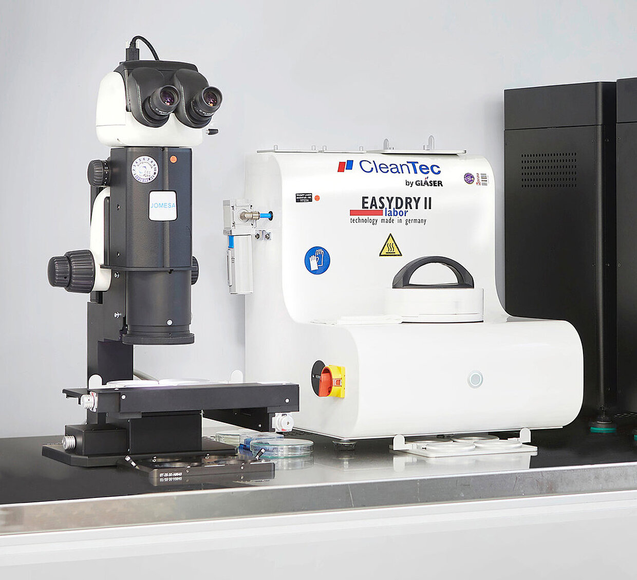 Laborgeräte für industrielle Reinigung und Analyse. Laborgeräte auf einem Tisch, darunter ein Mikroskop und eine Reinigungsmaschine.