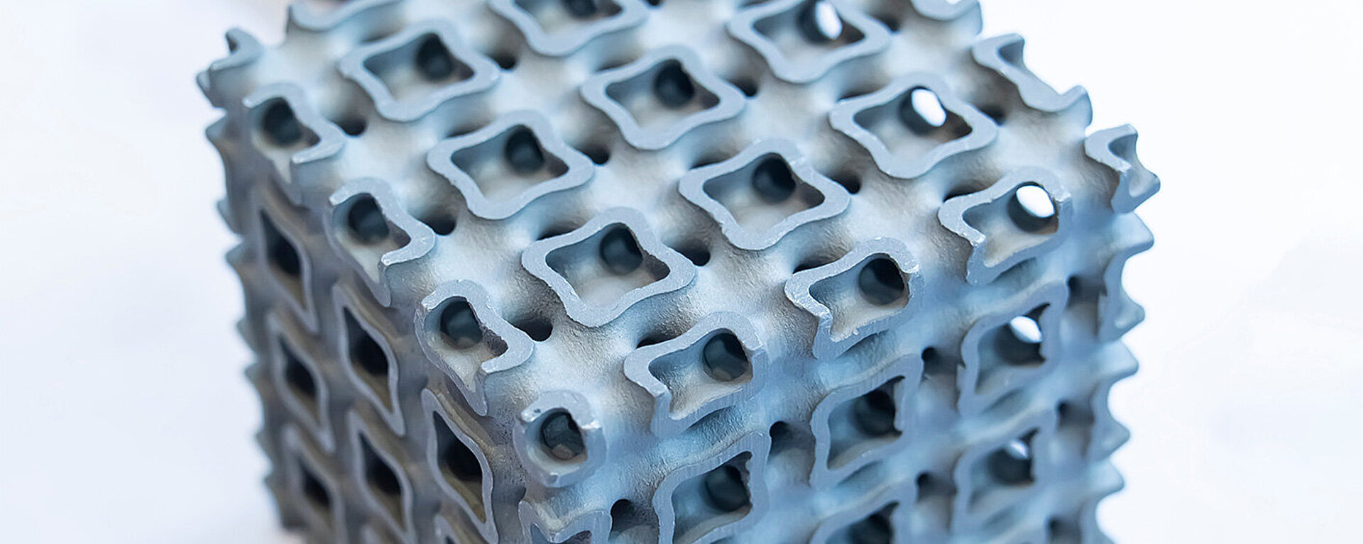 Nahaufnahme eines hellblauen perforierten Würfels, gedruckt auf einem Metall-3D-Drucker