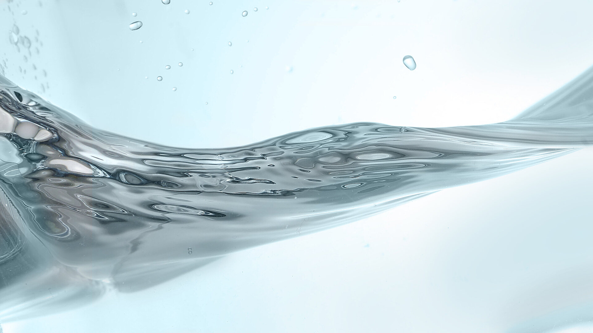 Nahaufnahme einer fließenden Wasserbewegung mit klaren Reflexionen und Wassertropfen, symbolisierend Reinheit, Dynamik und Präzision in der Reinigungstechnologie.