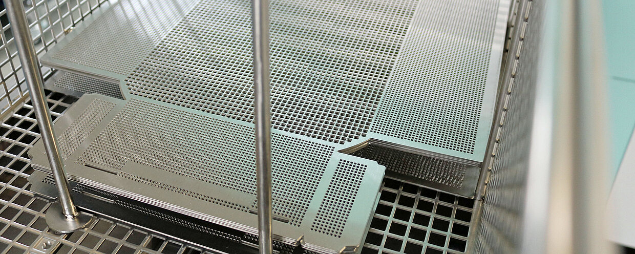Metallgitter und -platten in einem industriellen Reinigungsbehälter.